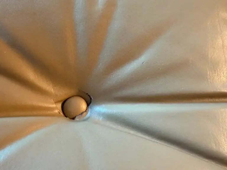 Leather wear around the button on the cushion before repair