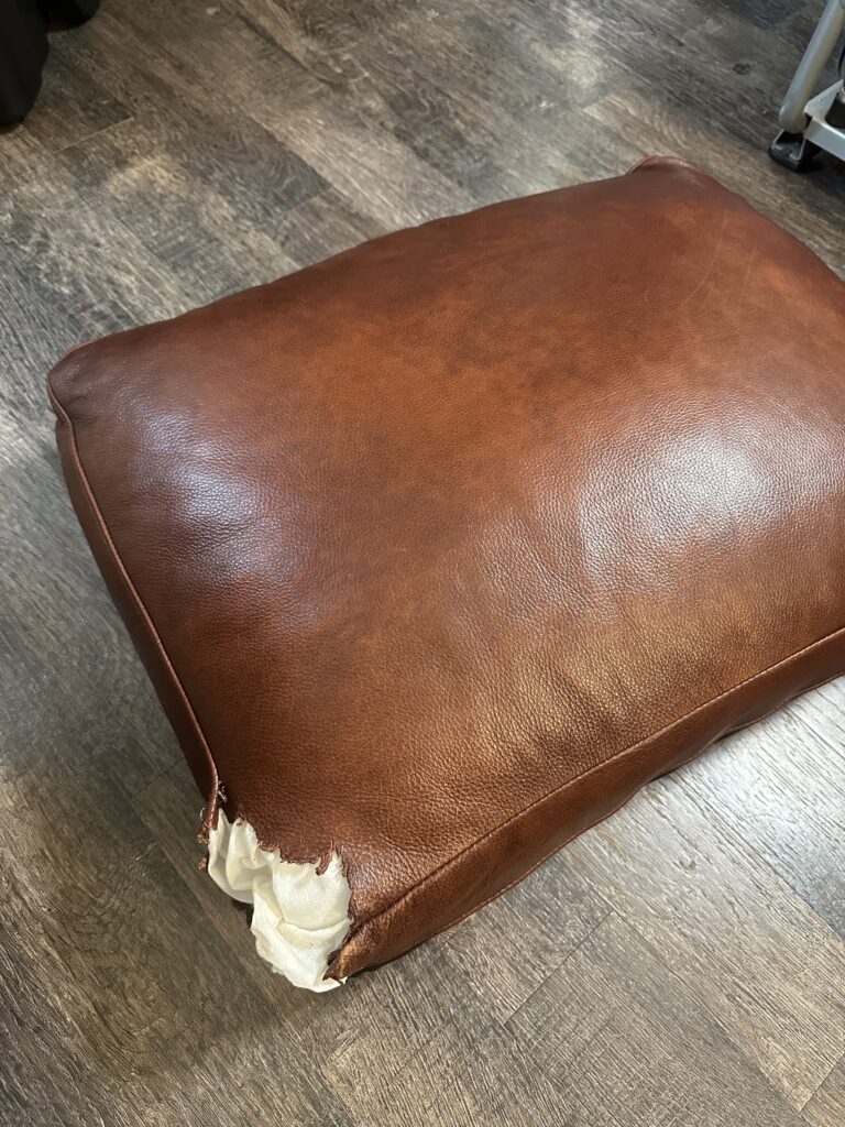 Cushion torn by a dog: new leather sewn, color matched (before)