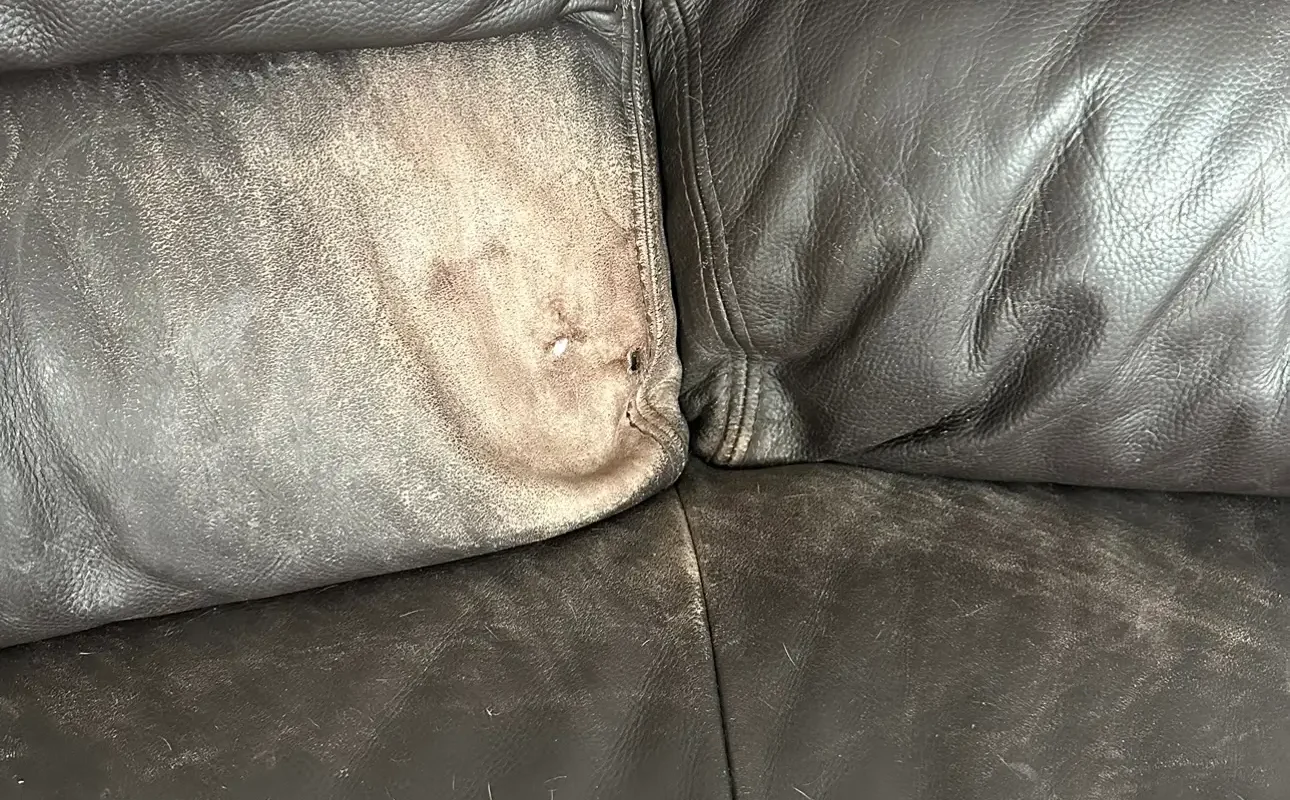 Worn leather couch with damage
